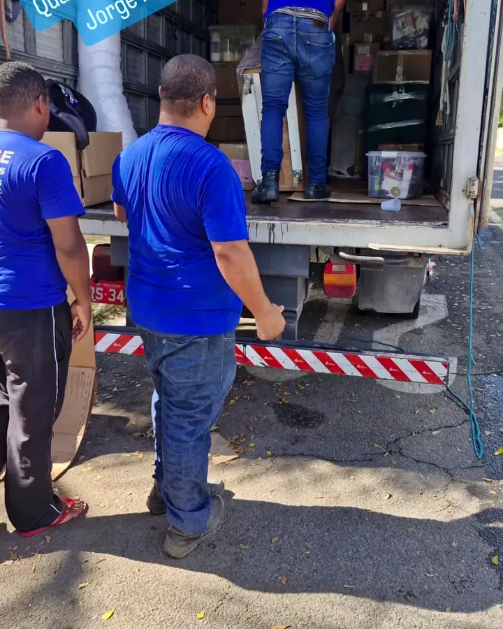 Equipe de farda azul carregando o baú do caminhão